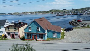 A coastal town with houses by the water, a dock, and a clear sky. - Jagged Rocks (Twillingate)