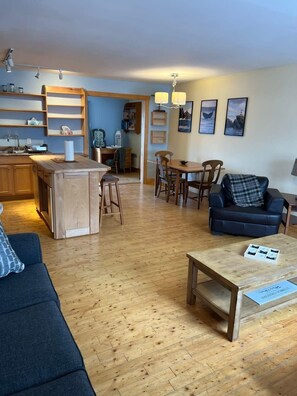 A cozy living room with a sofa, a coffee table, and a dining area with chairs and a table.