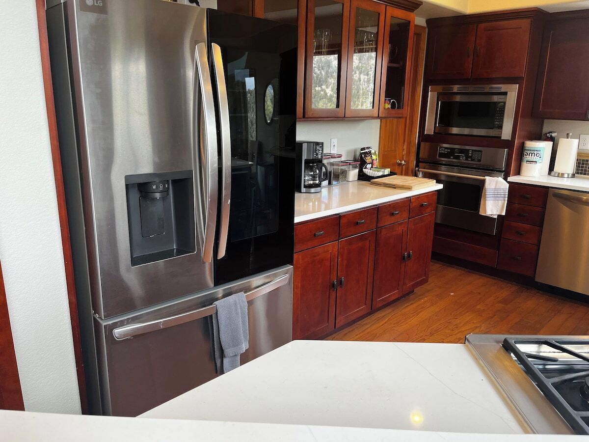 Una cocina con electrodomésticos de acero inoxidable, armarios de madera y encimera blanca.