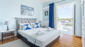 A hotel room with a bed, a nightstand, a lamp, a painting, and a view of the outside. - "Lux 3-bedroom Villa - L&L Refuge" (Nea Makri)