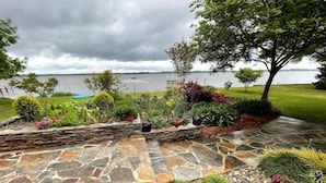 A landscaped garden with a stone pathway leading to a seating area by the water. - Little piece of heaven in your own back yard! (New Bern)