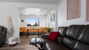 A modern living room with a leather sofa, a dining table, and a kitchen area in the background. - Very spacious, clean and tastefully remodeled home (Green Bay)