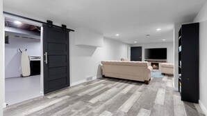 A modern living room with a large sliding door, a beige sofa, and a flat-screen TV. - Very spacious, clean and tastefully remodeled home (Green Bay)