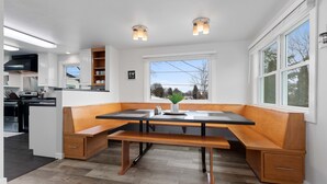 A modern kitchen with a built-in bench seating area, a large window with a view, and a black range hood. - Very spacious, clean and tastefully remodeled home (Green Bay)