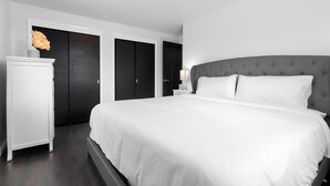 A modern bedroom with a large bed, a bedside table with a lamp, and a wardrobe. - Very spacious, clean and tastefully remodeled home (Green Bay)