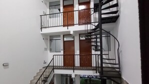 Un edificio a più livelli con una scala a chiocciola centrale, numerosi balconi e un piccolo cortile con erba sintetica.
