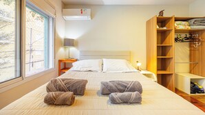 Una habitación de hotel con cama, armario, mesita de noche y ventana.