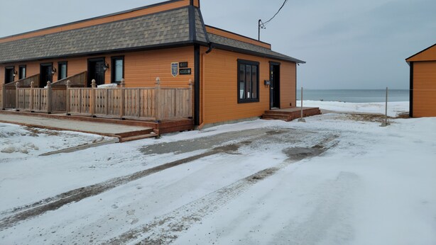 A wooden building with a grey roof, a wooden fence, and a sign indicating the number 680. - Motel Au Bord de l'eau (Rimouski)