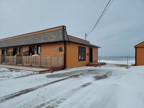 A wooden building with a grey roof, a wooden fence, and a sign indicating the number 680. - Motel Au Bord de l'eau (Rimouski)