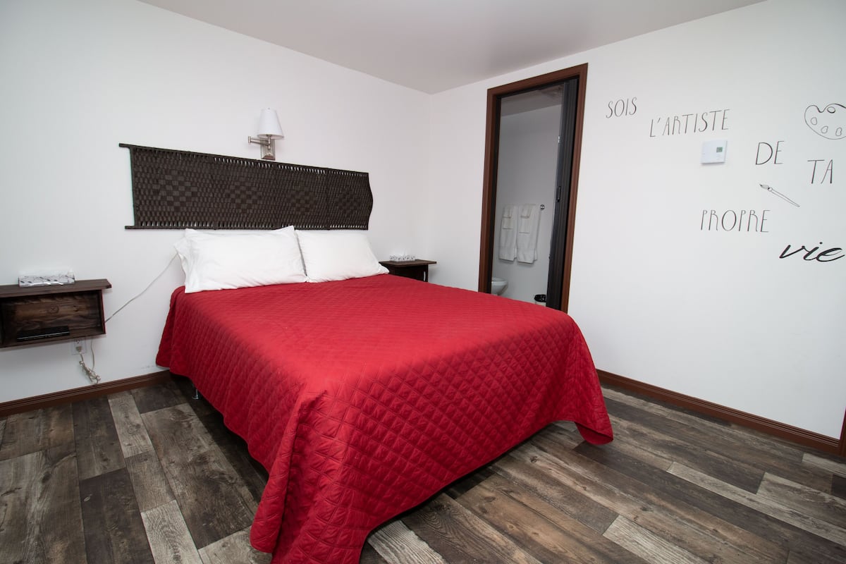 Ein Schlafzimmer mit einem Bett, einem Nachttisch, einer Lampe und einer Wand mit Text.