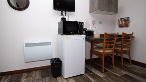 A compact kitchenette with a microwave, refrigerator, and a small dining table with chairs. - Motel Au Bord de l'eau (Rimouski)