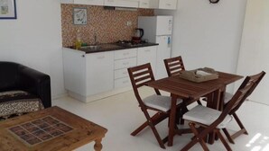 Un espace de vie compact comprenant un coin repas, une kitchenette et un canapé.