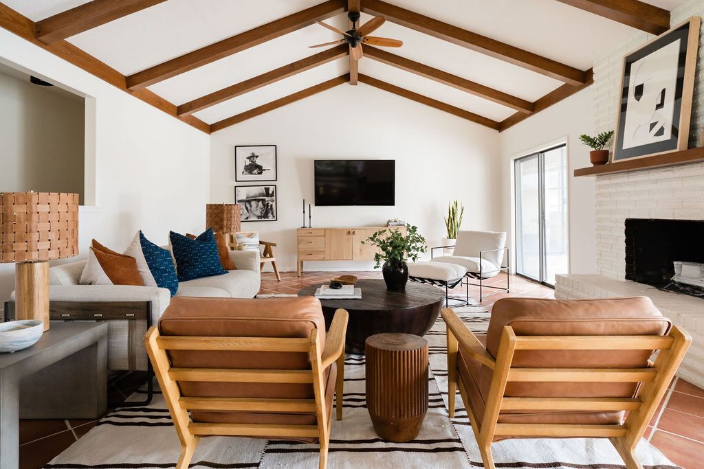 Un salón espacioso con techo alto, vigas de madera, chimenea y televisor.