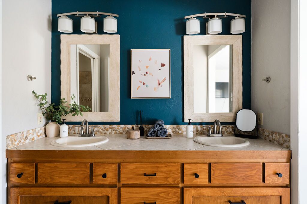 Une salle de bain avec deux lavabos, un meuble-lavabo en bois et des murs de couleur turquoise.