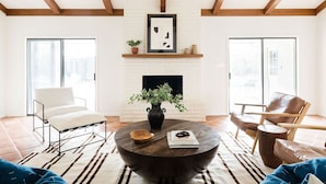 Un salon avec une cheminée, une table basse ronde et deux fauteuils.