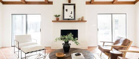Una sala de estar con chimenea, una mesa de centro redonda y dos sillones.