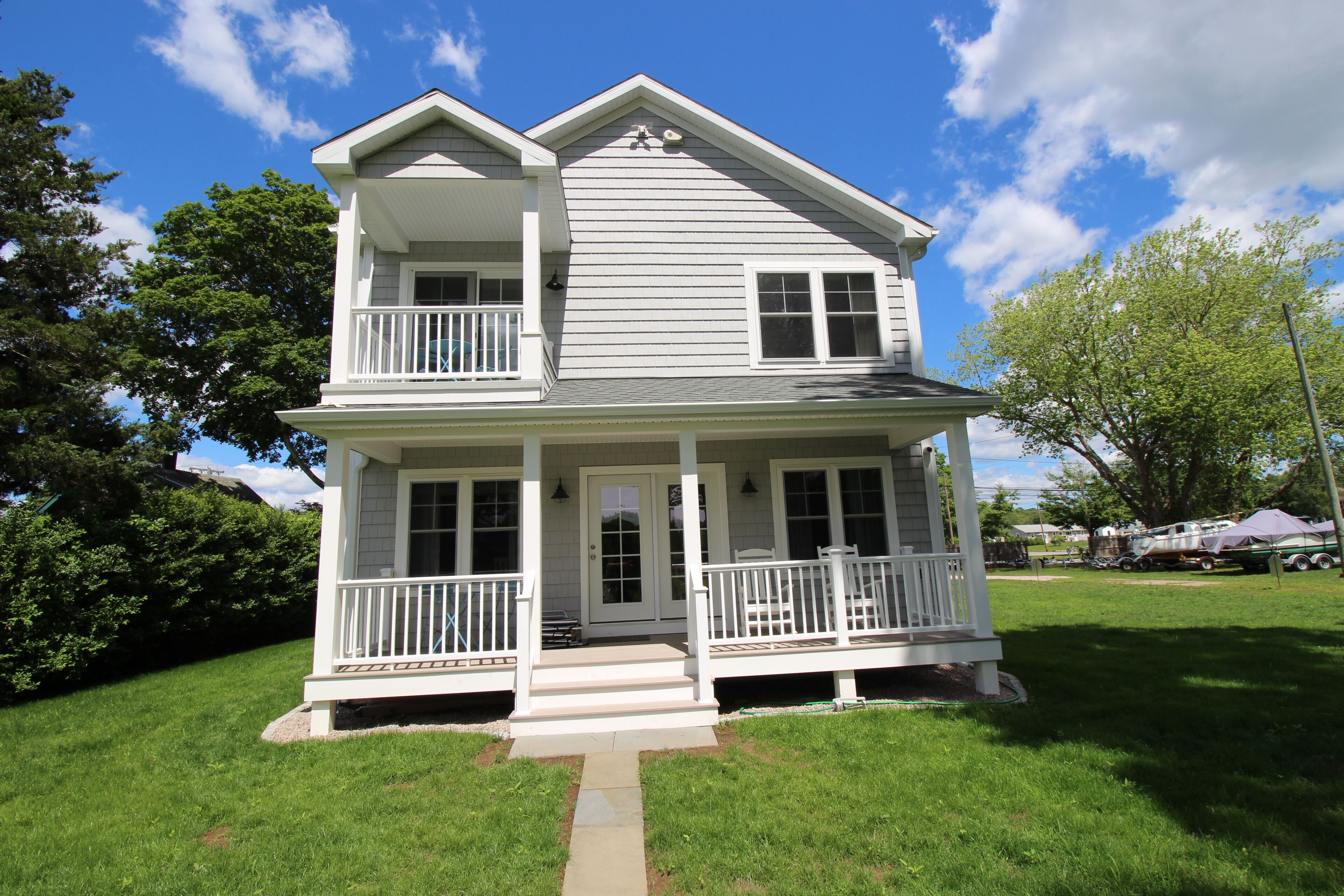 A two-story house with a front porch, a balcony on the upper floor, and a small front yard.