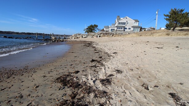 Une plage avec une grande maison en arrière-plan.