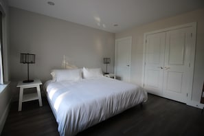 A bedroom with a large bed, two bedside tables, a wardrobe, and a window.