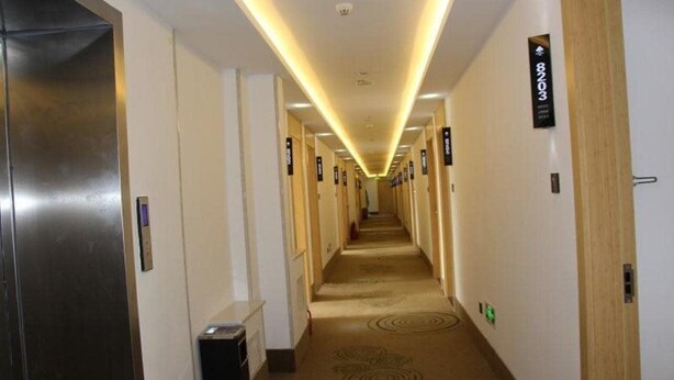 Un pasillo de hotel largo, con puertas numeradas y piso alfombrado.
