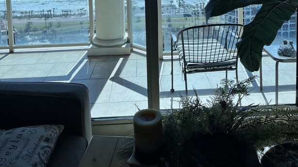 En balkon med udsigt over havet og en bygning i baggrunden.