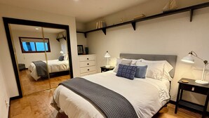 A bedroom with a large bed, bedside tables, a mirror, and a shelf above the bed. - Beautiful Canyon View Suite, 1100 sq. ft., private deck, full kitchen (Oakland)