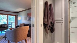 A hallway with a wooden floor, a grey wall, and a door. There are two towels hanging on the wall. - Beautiful Canyon View Suite, 1100 sq. ft., private deck, full kitchen (Oakland)