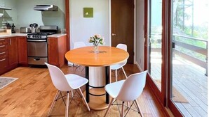 A kitchen with a wooden table and white chairs, a stove, and a window overlooking a deck. - Beautiful Canyon View Suite, 1100 sq. ft., private deck, full kitchen (Oakland)