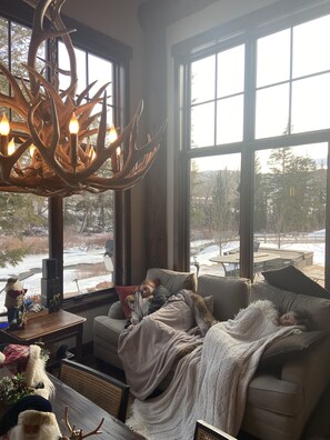 A cozy living room with a large window, a fireplace, and a comfortable couch.