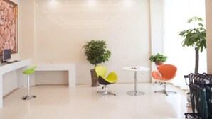 Un vestíbulo moderno y luminoso, con un mostrador de recepción, sillas coloridas y plantas en macetas.