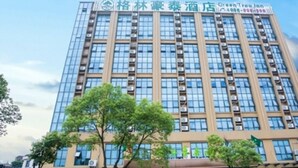 Un edificio alto de hotel con varios pisos y un letrero que indica que es un Green Tree Inn.