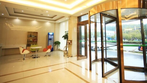 Un moderno vestíbulo con puerta giratoria, mostrador de recepción y una zona de estar con sillones.