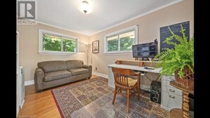 A living room with a sofa, a desk with a computer, a chair, a rug, and a plant.