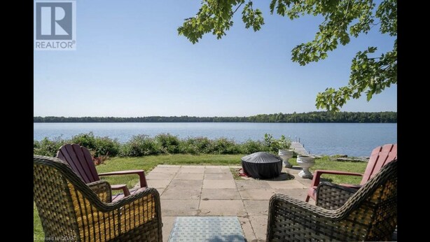 A patio with wicker chairs and a table overlooking a lake.