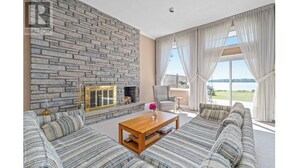 A living room with a stone fireplace, a sofa set, a coffee table, and a view of the outdoors.