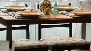 A dining table with four chairs, a skull centerpiece, and a tall candle. - Charming 2-BR House offering WIFI, Parking and a Garden | On Site Stays Welling (Welling)