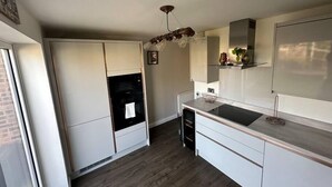 A modern kitchen with white cabinetry, a black oven, a built-in microwave, and a stainless steel sink. - Charming 2-BR House offering WIFI, Parking and a Garden | On Site Stays Welling (Welling)