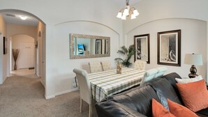 A living room with a dining table, a sofa, and a chandelier.
