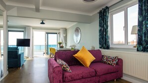 A living room with a purple sofa, a TV, and a view of the sea. - 3 bedroom accommodation in Hayling Island (Hayling Island)