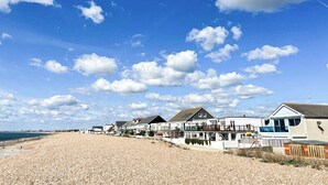 A coastal area with a pebble beach, seaside houses, and a clear blue sky. - 3 bedroom accommodation in Hayling Island (Hayling Island)