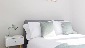 Ein ordentlich eingerichtetes Schlafzimmer mit Bett, Nachttisch und Wandbild.