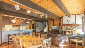 Un intérieur chaleureux avec une table à manger en bois, un coin bar et une cheminée en pierre.