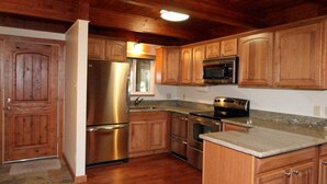Una cocina con armarios de madera, electrodomésticos de acero inoxidable y encimera de granito.