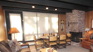 Un salon chaleureux avec une cheminée, une table à manger avec des chaises et un canapé.
