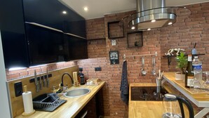 Una cocina moderna con pared de ladrillo, electrodomésticos de acero inoxidable, encimeras de madera y un colgador para cuchillos.