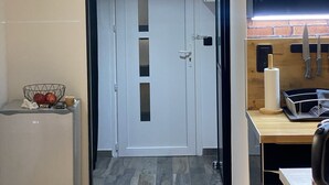 Una cocina moderna con una puerta blanca, una encimera con un escurreplatos y un colgador para cuchillos.
