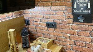Una cocina con pared de ladrillo, un televisor de pantalla plana montado sobre una encimera de madera, un enfriador de vino y un cartel con texto en francés.