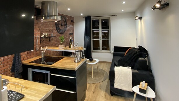 Un espacio habitable compacto con cocina, mesa de comedor, sofá y una mesita auxiliar.