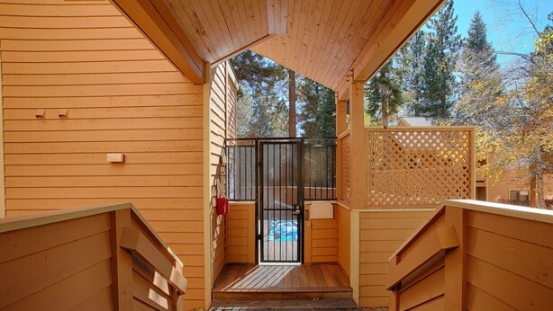 A wooden staircase leading to a door with a metal gate, surrounded by wooden walls and a lattice fence. - Condo at the popular McCloud complex (MC255) (Incline Village)
