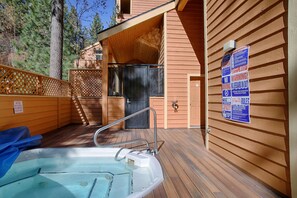 Eine Holzterrasse mit Whirlpool, Holzwänden und einer Tür.